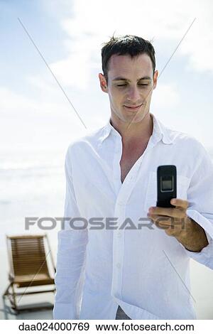Young man using cell phone on beach View Large Photo Image Stock Photo - Young man using cell phone on beach. Fotosearch