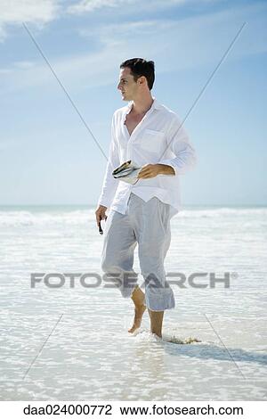 Young man walking through surf, looking away View Large Photo Image Stock Image - Young man walking through surf, looking away. Fotosearch