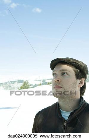 Young man wearing hat in snowy landscape, looking up View Large Photo Image Stock Photography - Young man wearing hat in snowy landscape, looking up. Fotosearch