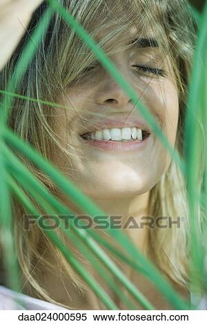 Young woman among foliage, hair in face, smiling, eyes closed View Large Photo Image Stock Photography - Young woman among foliage, hair in face, smiling, eyes closed. Fotosearch
