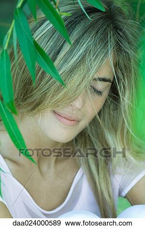 Young woman among foliage, hair covering face, eyes closed View Large Photo Image Stock Photo - Young woman among foliage, hair covering face, eyes closed. Fotosearch