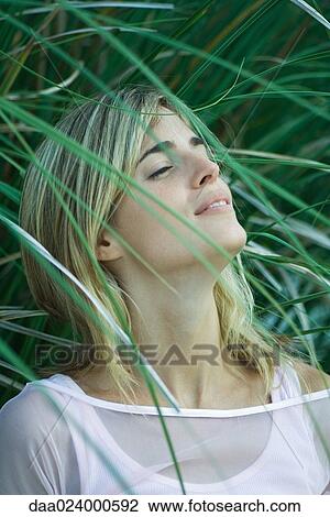Young woman among foliage, head back, eyes half-opened View Large Photo Image Stock Image - Young woman among foliage, head back, eyes half-opened. Fotosearch