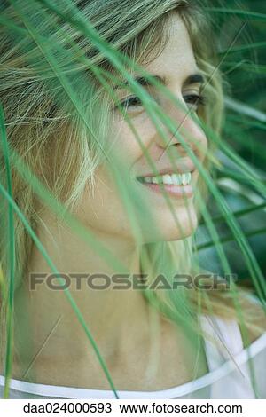 Young woman among foliage, looking away, smiling View Large Photo Image Stock Image - Young woman among foliage, looking away, smiling. Fotosearch