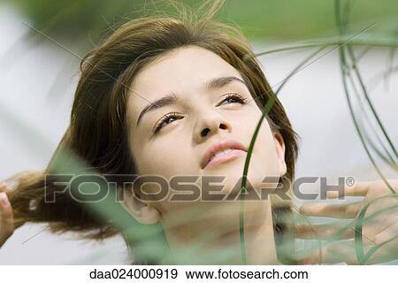 Young woman among tall grass, looking up, portrait View Large Photo Image Stock Photo - Young woman among tall grass, looking up, portrait. Fotosearch