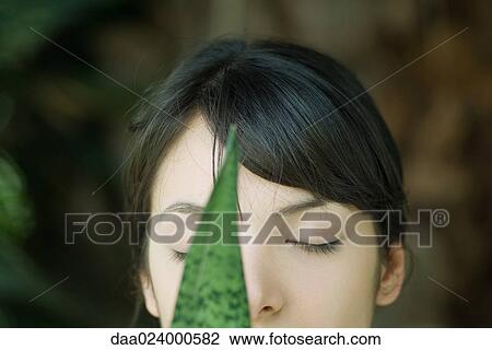 Young woman behind leaf, eyes closed, cropped portrait View Large Photo Image Stock Image - Young woman behind leaf, eyes closed, cropped portrait. Fotosearch