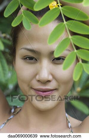 Stock Photo - Young woman behind leaves. Fotosearch