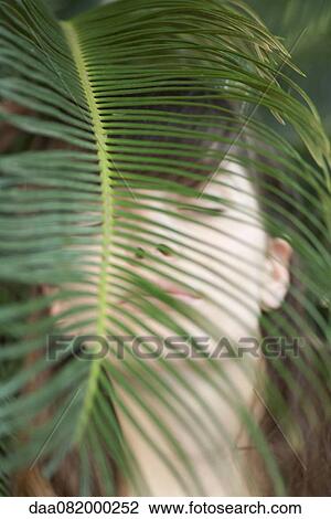 Young woman behind palm frond, eyes closed View Large Photo Image Stock Image - Young woman behind palm frond, eyes closed. Fotosearch