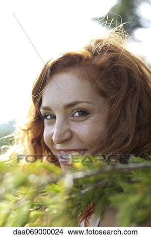Young woman behind tree branch, portrait View Large Photo Image Picture - Young woman behind tree branch, portrait. Fotosearch