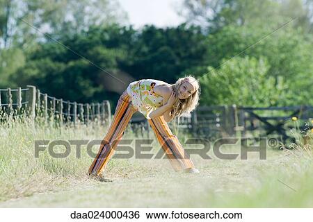 Young woman bending over in rural field with arms folded, smiling at camera View Large Photo Image Stock Photograph - Young woman bending over in rural field with arms folded, smiling at camera. Fotosearch