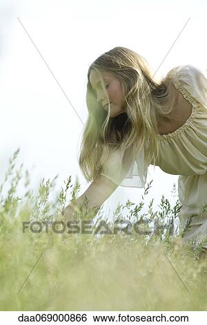 Young woman bending over tall grass View Large Photo Image Stock Photograph - Young woman bending over tall grass. Fotosearch