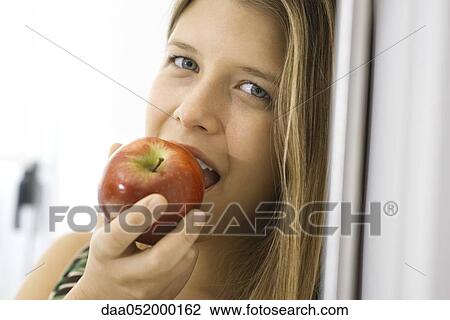 Young woman biting into apple View Large Photo Image Stock Image - Young woman biting into apple. Fotosearch