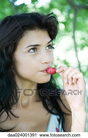 Young woman biting into radish, looking up View Large Photo Image Stock Image - Young woman biting into radish, looking up. Fotosearch