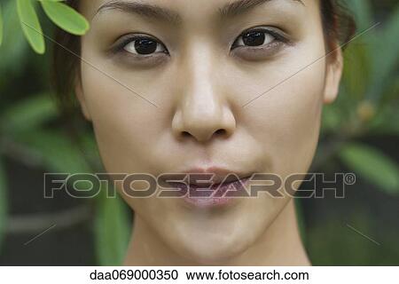 Stock Image - Young woman blowing cigarette smoke. Fotosearch