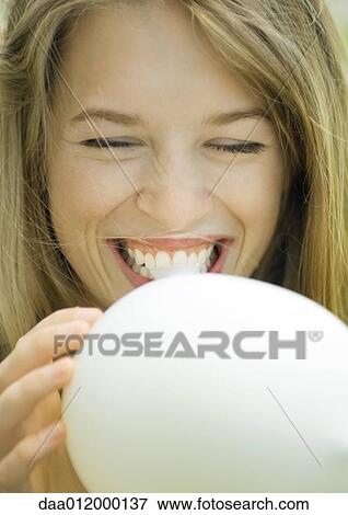 Young woman blowing up balloon, laughing, close-up View Large Photo Image Stock Photo - Young woman blowing up balloon, laughing, close-up. Fotosearch