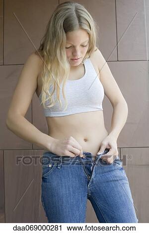 Young woman buttoning tight jeans View Large Photo Image Stock Image - Young woman buttoning tight jeans. Fotosearch