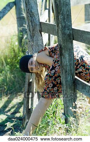 Young woman climbing through wooden fence, smiling at camera View Large Photo Image Stock Photography - Young woman climbing through wooden fence, smiling at camera. Fotosearch