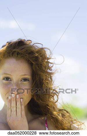 Stock Photo - Young woman covering mouth with hand, portrait. Fotosearch