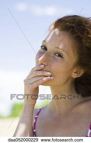 Young woman covering mouth with hand, portrait View Large Photo Image Stock Photo - Young woman covering mouth with hand, portrait. Fotosearch