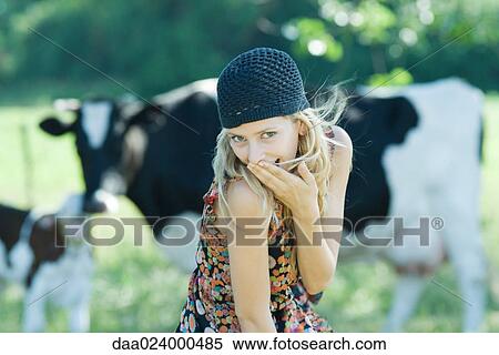 Young woman covering mouth with hand, looking at camera, cows in background View Large Photo Image Stock Photography - Young woman covering mouth with hand, looking at camera, cows in background. Fotosearch