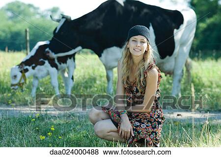 Young woman crouching in front of cows, smiling at camera View Large Photo Image Stock Photo - Young woman crouching in front of cows, smiling at camera. Fotosearch