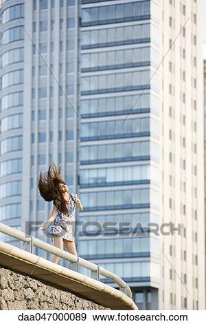 Stock Photo - Young woman dancing on balcony, tossing hair. Fotosearch
