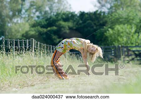 Stock Photo - Young woman doing backbend in rural field. Fotosearch