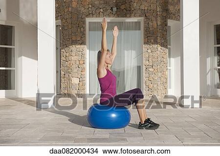 Picture - Young woman doing exercise on fitness ball with eyes closed. Fotosearch