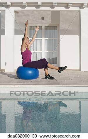 Young woman doing exercise on fitness ball at poolside View Large Photo Image Stock Image - Young woman doing exercise on fitness ball at poolside. Fotosearch