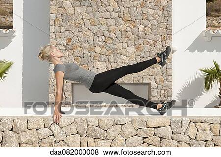 Young woman doing pilates exercise outdoors, eyes closed, side view View Large Photo Image Stock Photo - Young woman doing pilates exercise outdoors, eyes closed, side view. Fotosearch