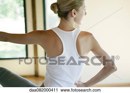 Stock Image - Young woman doing seated spinal twist, rear view. Fotosearch