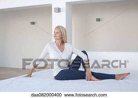 Young woman doing spinal twist yoga pose on bed outdoors View Large Photo Image Stock Image - Young woman doing spinal twist yoga pose on bed outdoors. Fotosearch