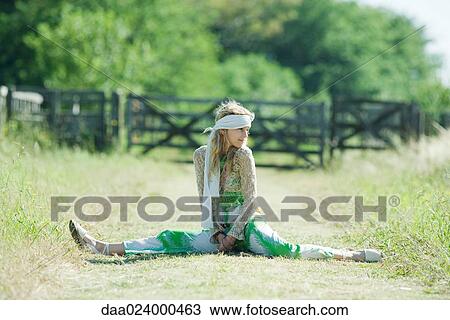 Stock Image - Young woman doing splits in rural field. Fotosearch