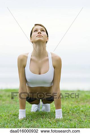 Stock Image - Young woman doing stretching exercises by lakeside. Fotosearch