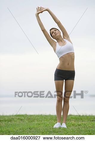 Young woman doing stretching exercises by lakeside View Large Photo Image Stock Photo - Young woman doing stretching exercises by lakeside. Fotosearch