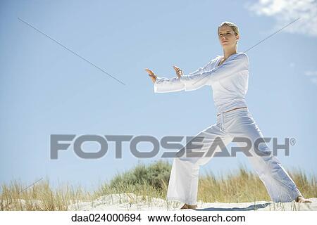 Young woman doing Tai Chi in dunes, full length View Large Photo Image Picture - Young woman doing Tai Chi in dunes, full length. Fotosearch