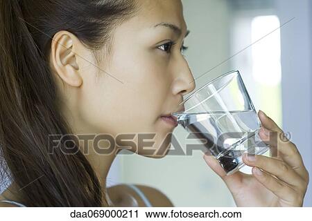 Stock Image - Young woman drinking glass of water. Fotosearch
