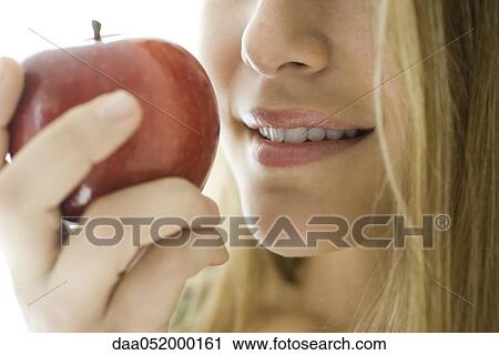 Stock Image - Young woman eating apple, close-up. Fotosearch