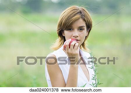 Young woman eating apple outdoors, head and shoulders View Large Photo Image Stock Photo - Young woman eating apple outdoors, head and shoulders. Fotosearch