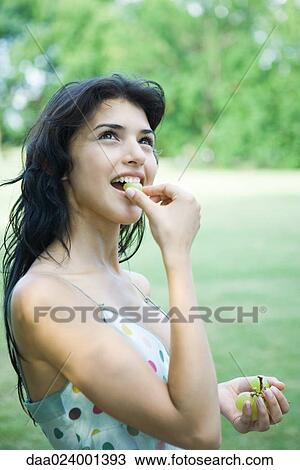 Young woman eating grapes, looking up View Large Photo Image Stock Image - Young woman eating grapes, looking up. Fotosearch