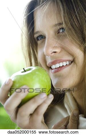 Stock Photography - Young woman eating green apple. Fotosearch