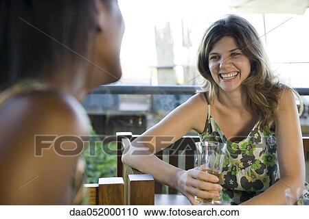Young woman having drinks with friend View Large Photo Image Stock Image - Young woman having drinks with friend. Fotosearch