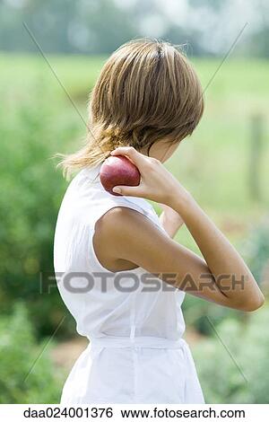 Young woman holding apple over shoulder, side view View Large Photo Image Stock Photograph - Young woman holding apple over shoulder, side view. Fotosearch