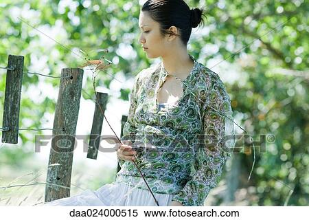 Young woman holding branch in rural setting View Large Photo Image Stock Photography - Young woman holding branch in rural setting. Fotosearch