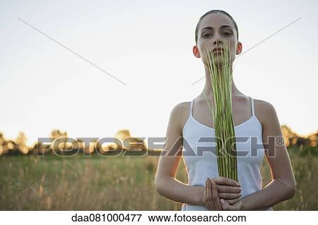 Young woman holding bundle of grass outdoors View Large Photo Image Stock Photo - Young woman holding bundle of grass outdoors. Fotosearch