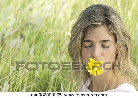Young woman holding daisy in mouth with eyes closed View Large Photo Image Stock Photography - Young woman holding daisy in mouth with eyes closed. Fotosearch