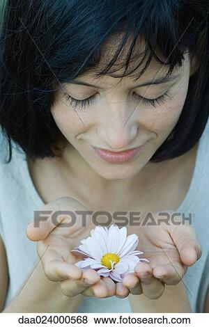 Young woman holding flower in cupped hands, eyes closed, high angle view View Large Photo Image Stock Photo - Young woman holding flower in cupped hands, eyes closed, high angle view. Fotosearch