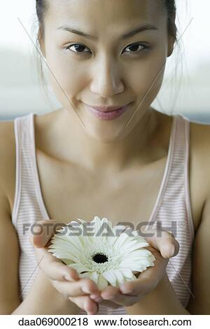 Stock Photo - Young woman holding gerbera daisy, portrait. Fotosearch