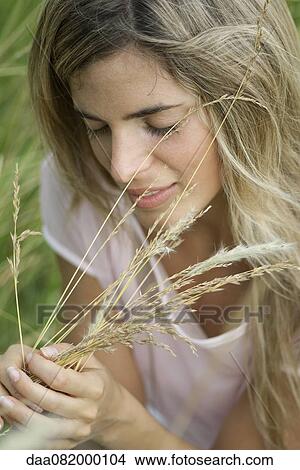 Young woman holding grass with eyes closed View Large Photo Image Picture - Young woman holding grass with eyes closed. Fotosearch