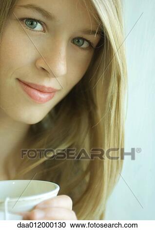 Stock Image - Young woman holding mug, portrait. Fotosearch