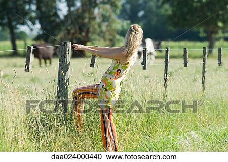 Young woman holding on to rural fence, side view View Large Photo Image Stock Image - Young woman holding on to rural fence, side view. Fotosearch